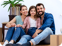 Familia sonriente de padre, madre e hija sentados juntos, con cajas de mudanza