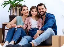 Familia sonriente de padre, madre e hija sentados juntos, con cajas de mudanza